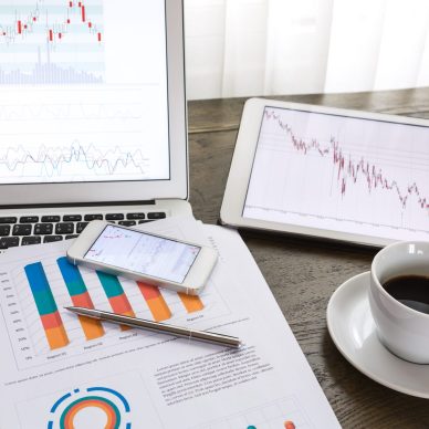 Laptop, tablet , smartphone and coffee cup with financial documents on wooden table